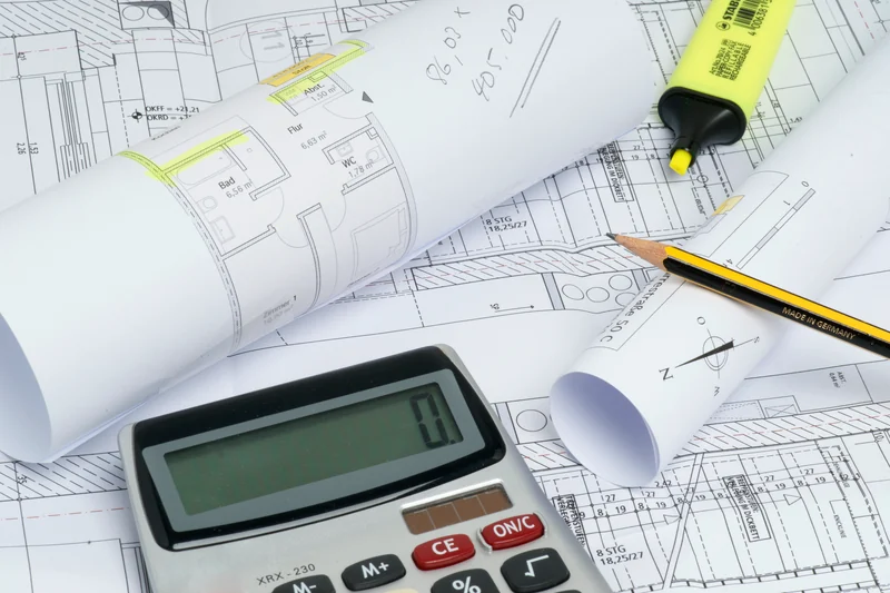 Taschenrechner auf Bauplänen als Motiv für die Immobilienbewertung